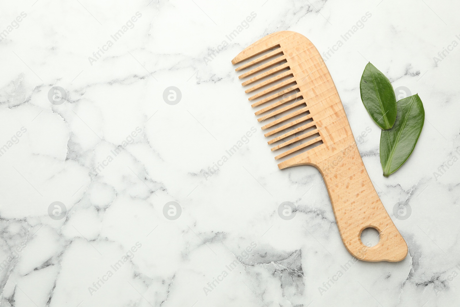 Photo of Wooden comb and leaves on white marble table, flat lay. Space for text