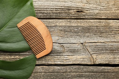 Photo of Comb and monstera leaf on wooden table, top view. Space for text