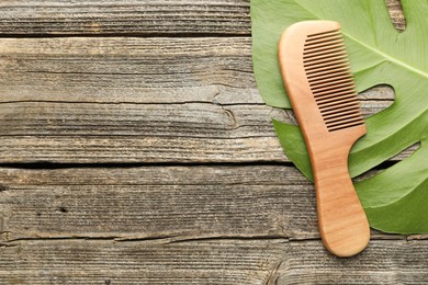 Photo of Comb and monstera leaf on wooden table, top view. Space for text