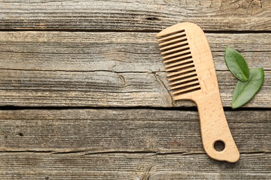 Photo of Comb and leaves on wooden table, flat lay. Space for text