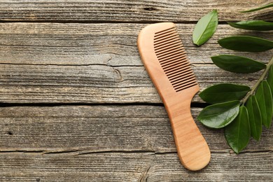 Photo of Comb and branch with leaves on wooden table, flat lay. Space for text