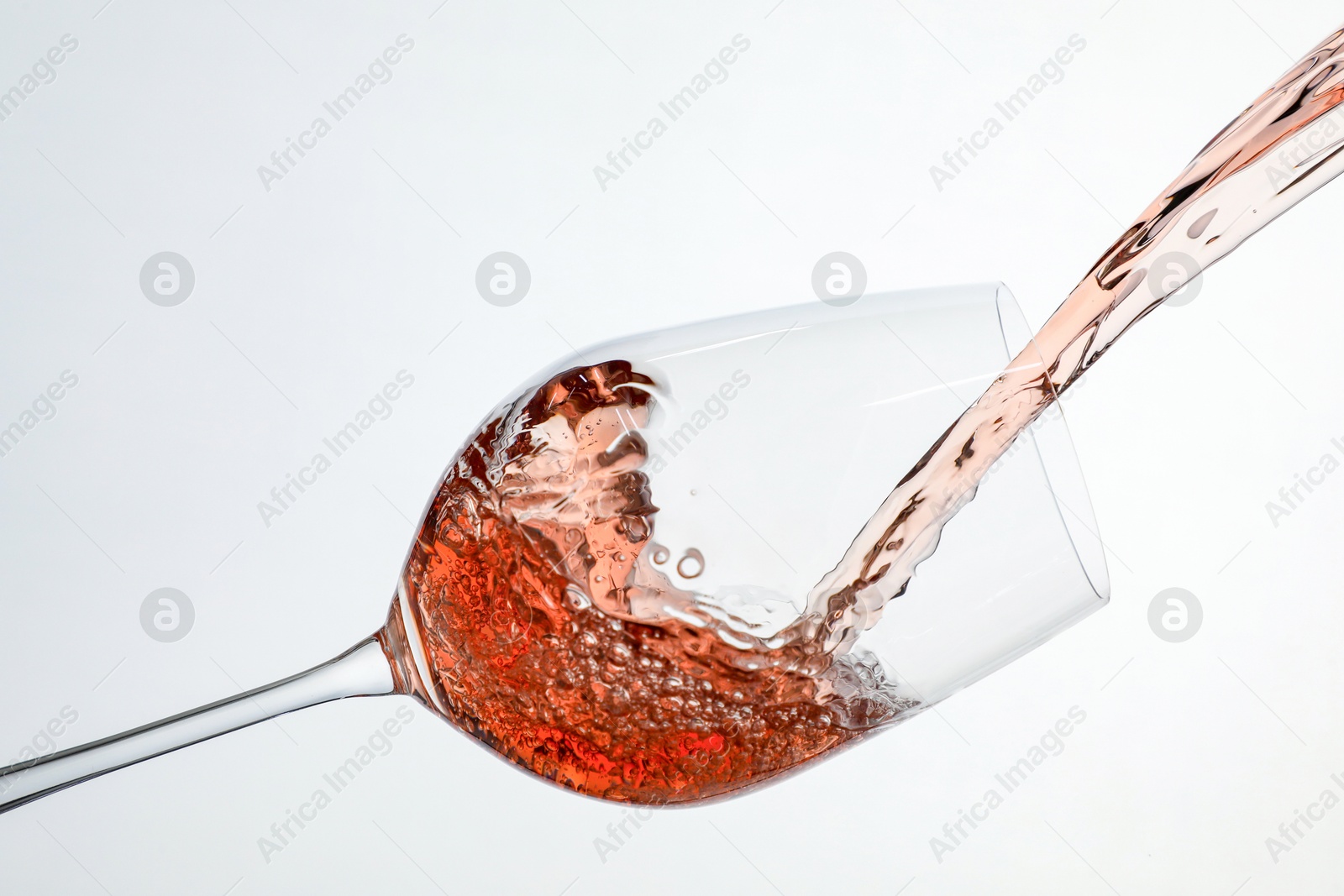 Photo of Pouring rose wine into glass on white background