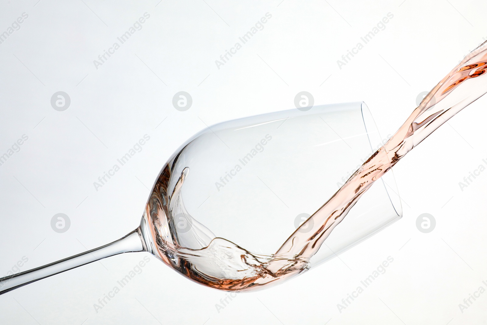 Photo of Pouring rose wine into glass on white background