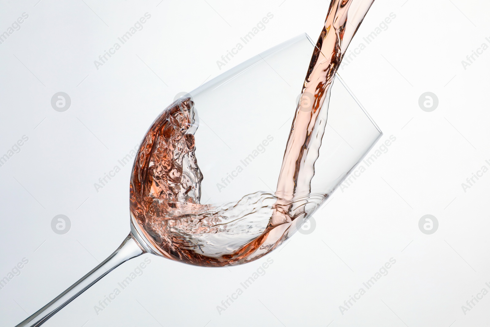 Photo of Pouring rose wine into glass on white background