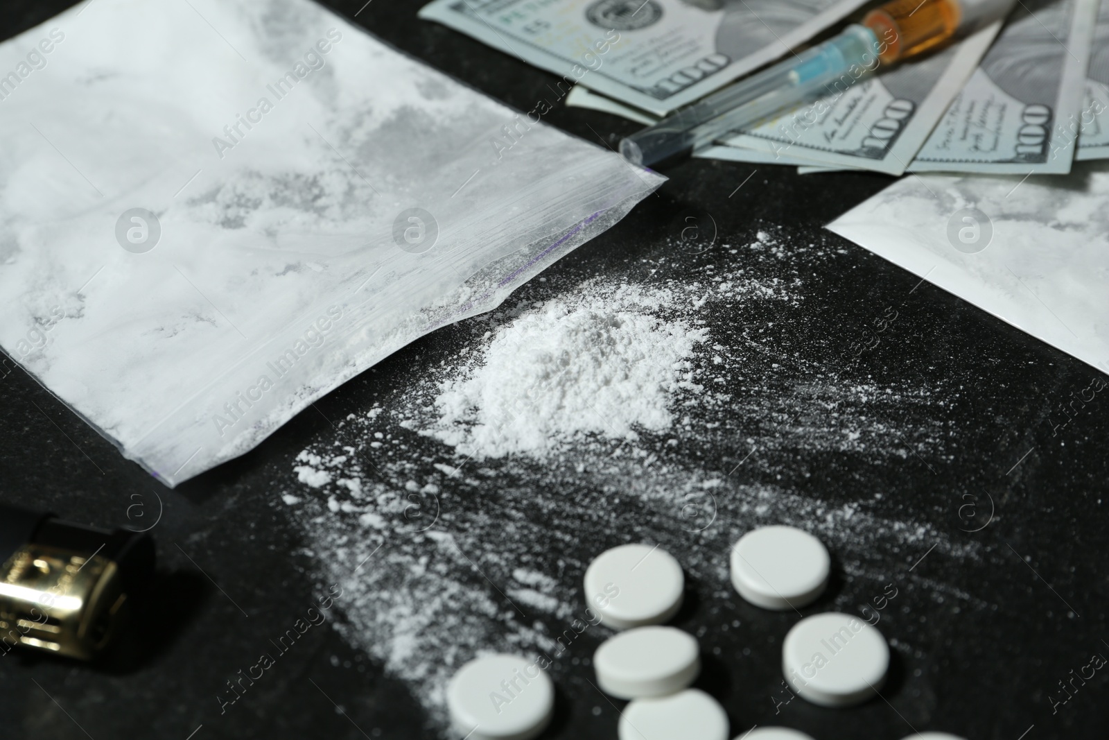 Photo of Drug addiction. Plastic bags with powder, pills, dollar banknotes and syringe on black textured table, closeup