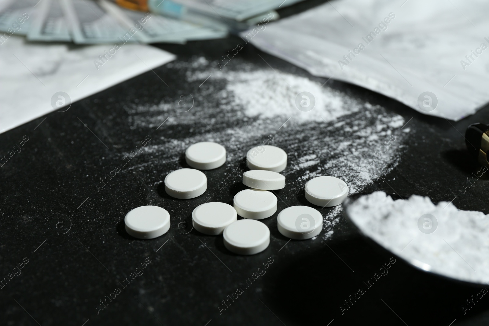 Photo of Drug addiction. Pills and powder on black textured table, closeup