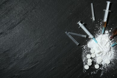 Photo of Drug addiction. Powder, pills and syringes on black textured table, flat lay. Space for text