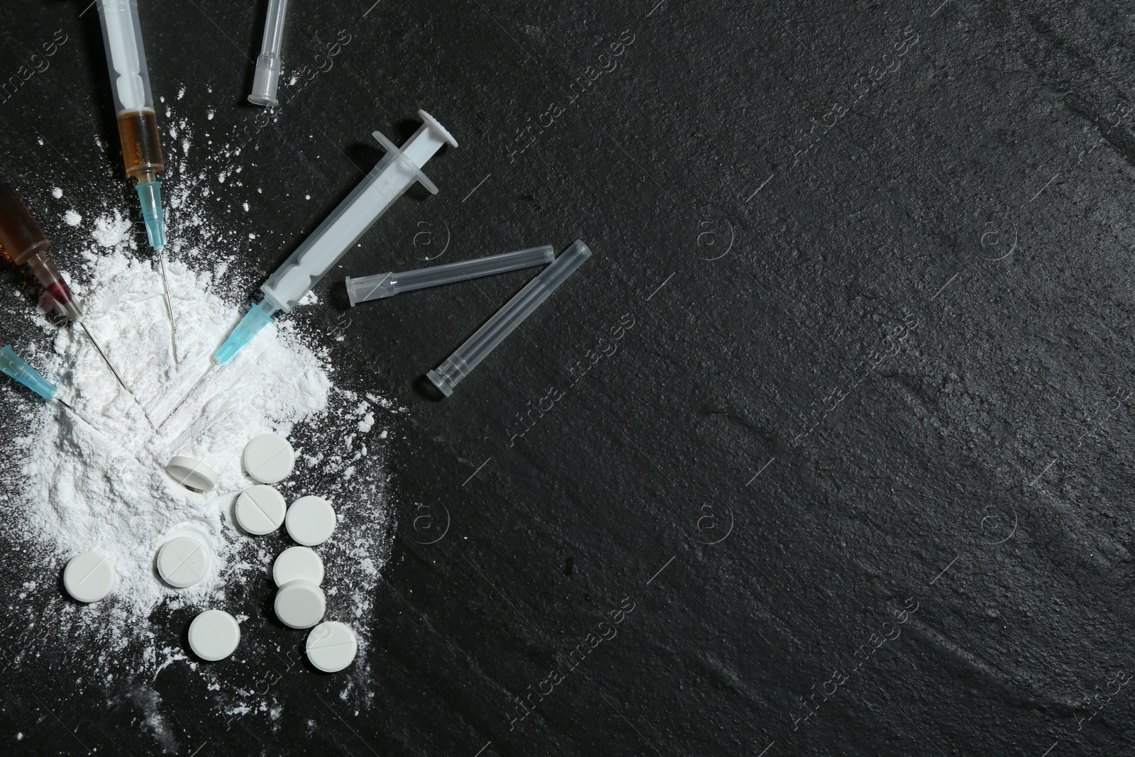 Photo of Drug addiction. Powder, pills and syringes on black textured table, flat lay. Space for text