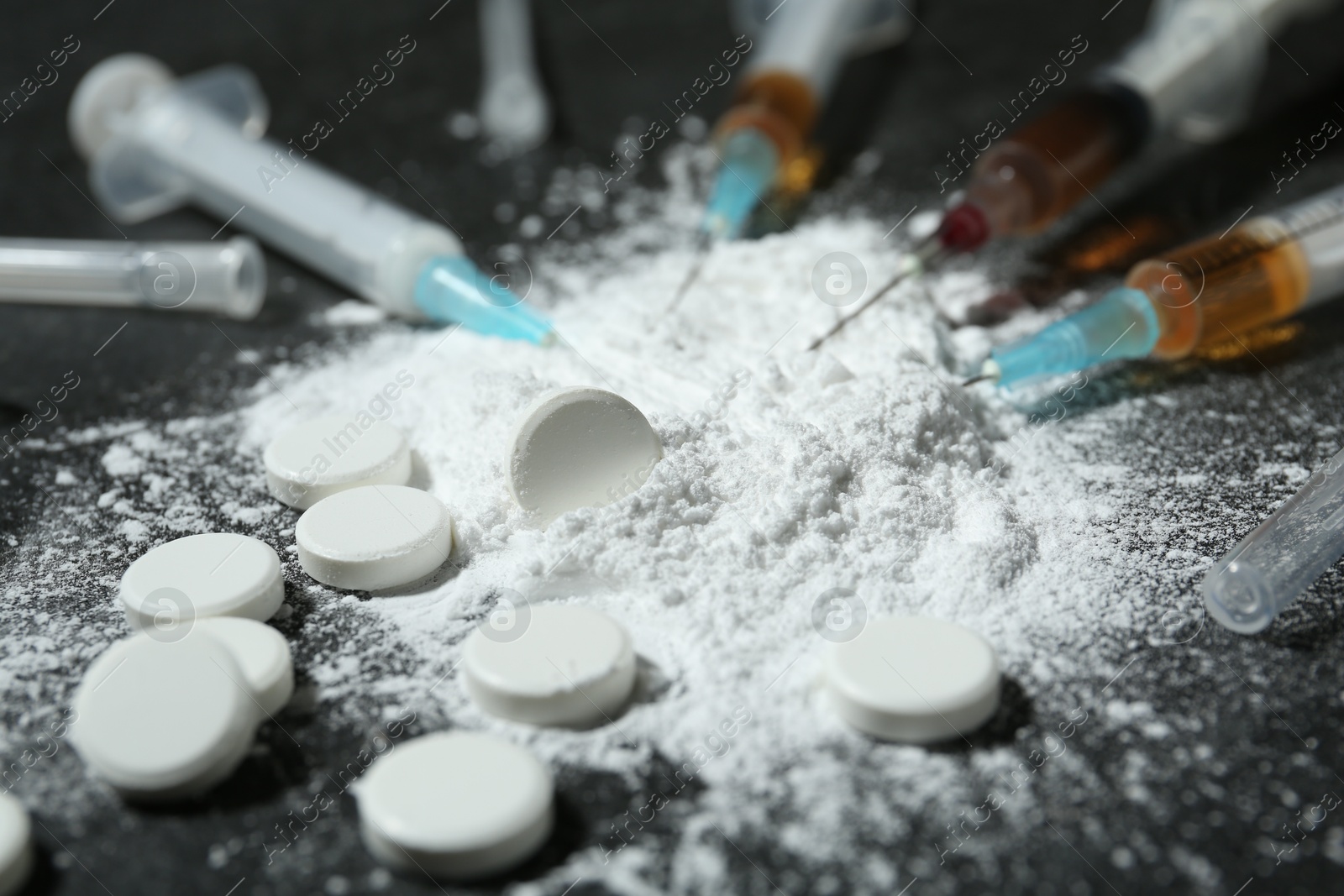 Photo of Drug addiction. Powder, pills and syringes on gray table, closeup