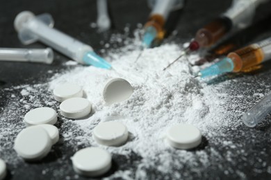 Photo of Drug addiction. Powder, pills and syringes on gray table, closeup