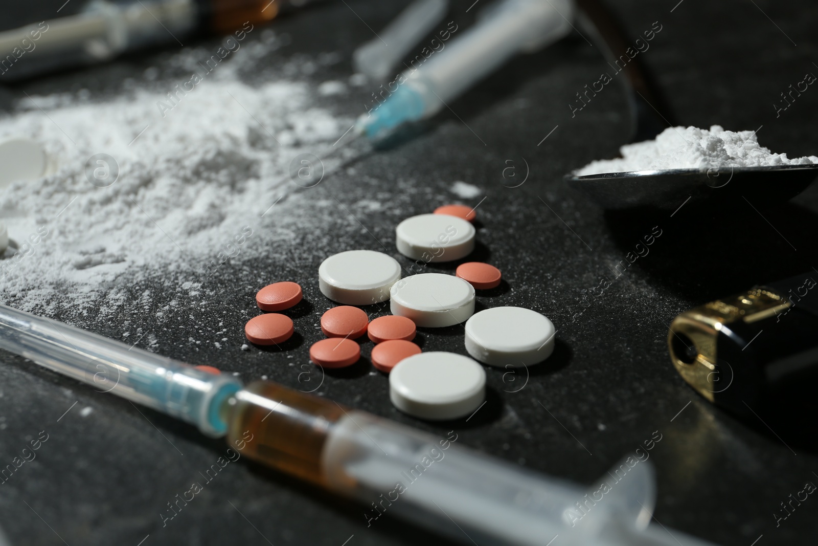 Photo of Drug addiction. Spoon with powder, pills, syringes and cigarette lighter on gray table, closeup