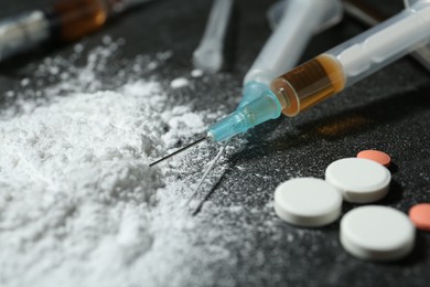 Photo of Drug addiction. Powder, pills and syringes on gray table, closeup