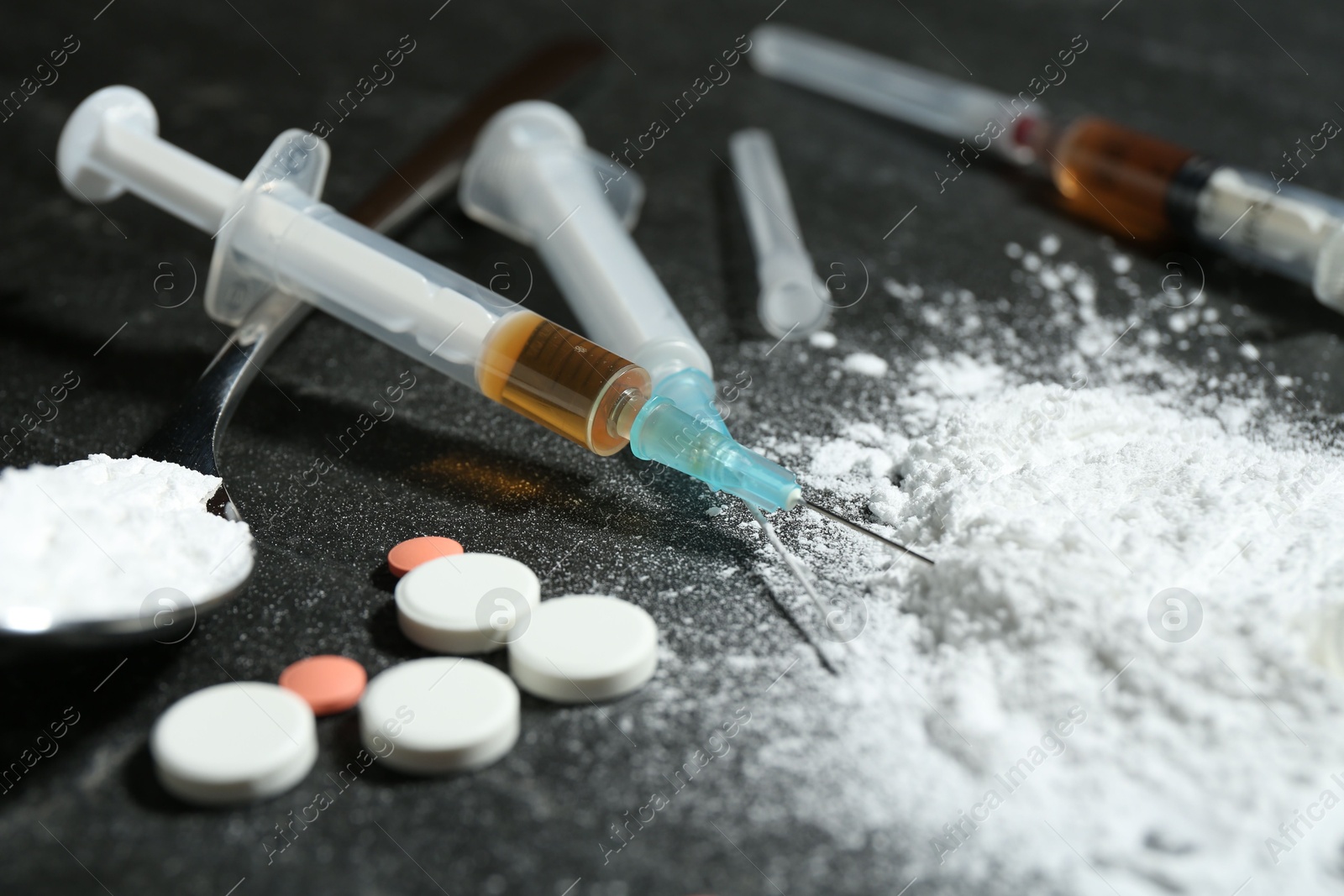 Photo of Drug addiction. Powder, pills and syringes on gray table, closeup