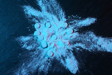 Photo of Drug addiction. Powder and pills on dark table in neon lights, top view