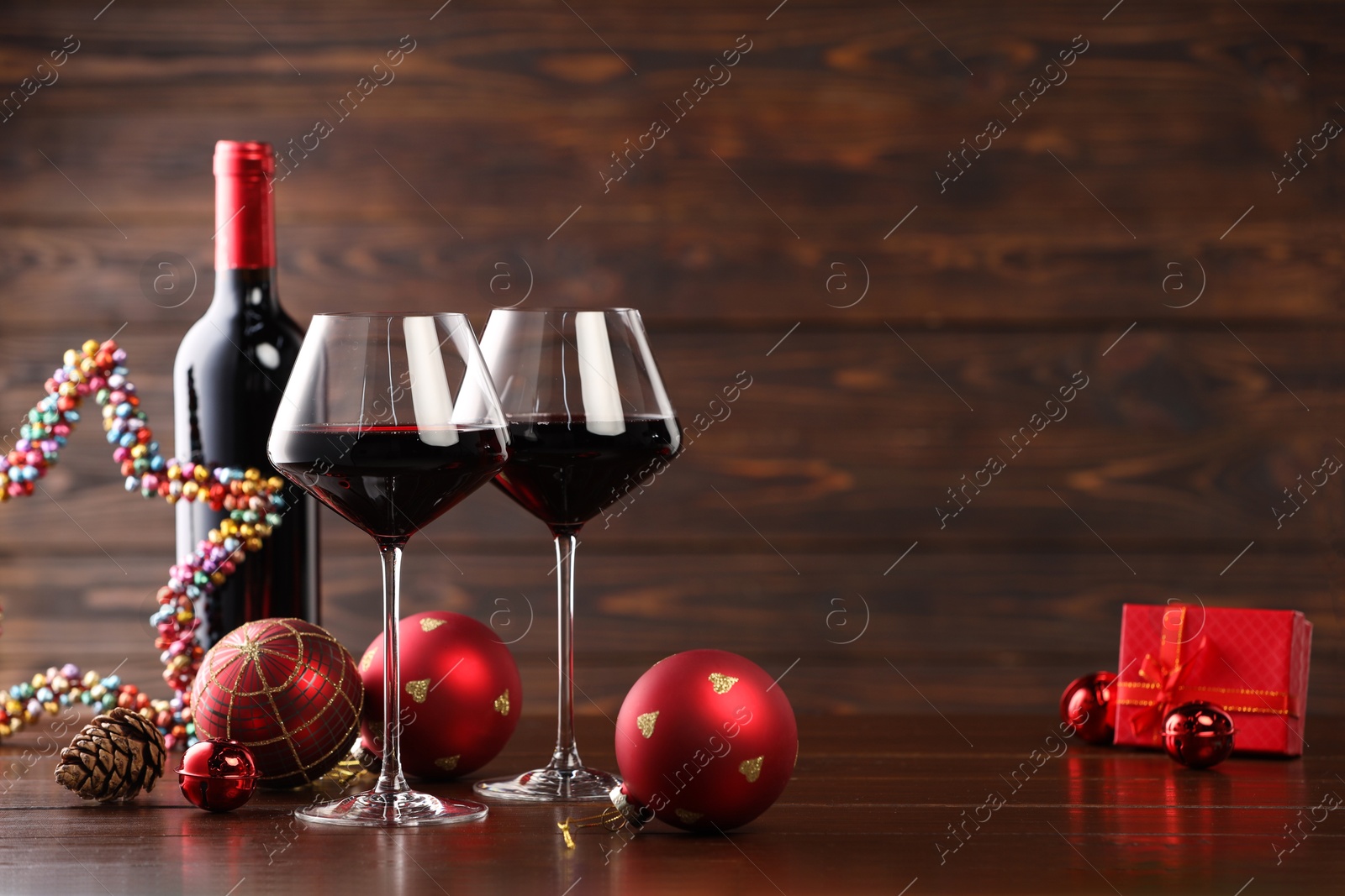 Photo of Red wine and beautiful Christmas decor on wooden table. Space for text