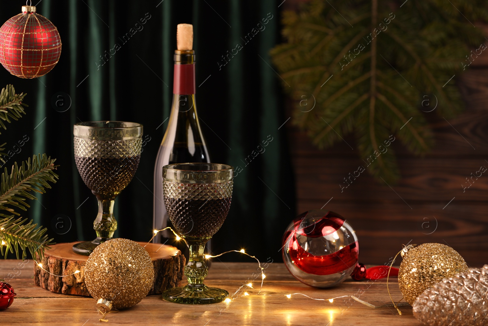 Photo of Red wine and beautiful Christmas decor on wooden table. Space for text