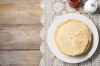 Photo of Delicious crepes and jam on wooden table, flat lay. Space for text