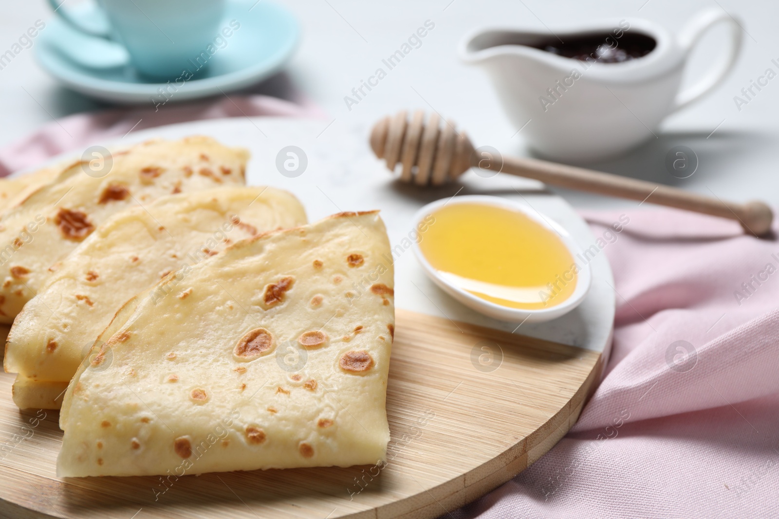 Photo of Delicious crepes and honey on light table, closeup