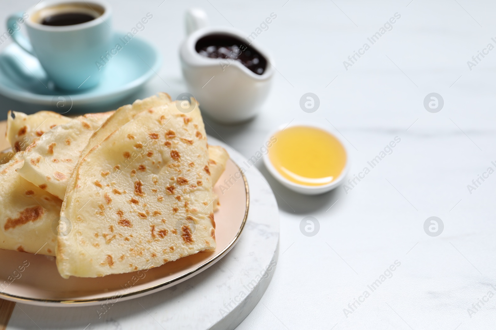 Photo of Delicious crepes served on white table, closeup. Space for text