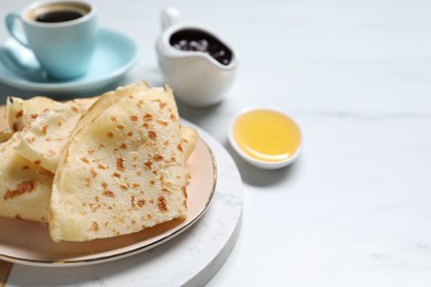 Photo of Delicious crepes served on white table, closeup. Space for text