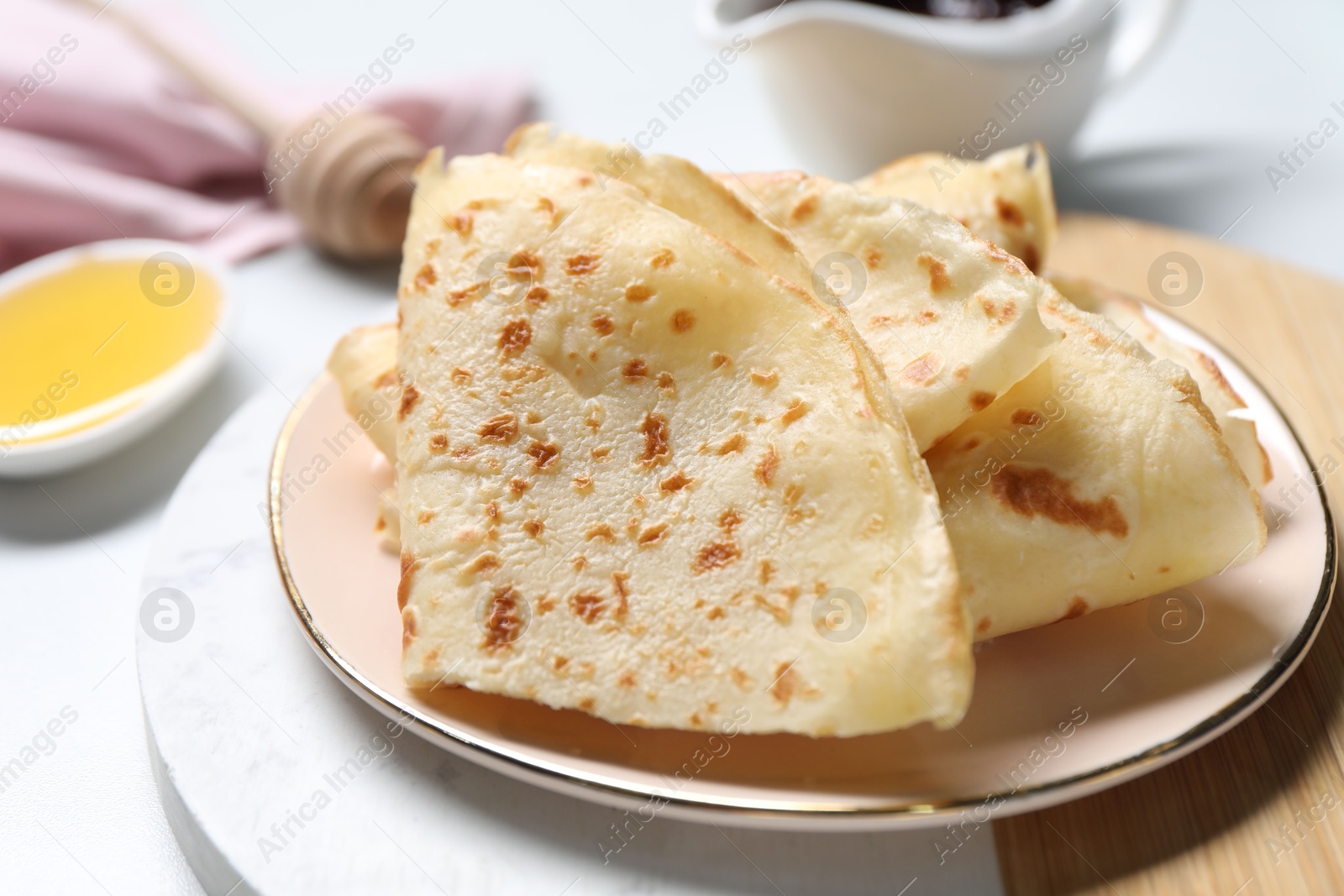 Photo of Plate with delicious folded crepes on white table, closeup