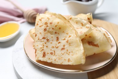 Photo of Plate with delicious folded crepes on white table, closeup