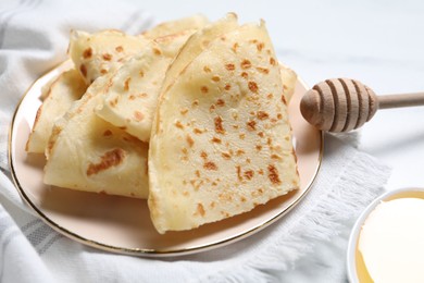 Photo of Delicious crepes and honey on white table, closeup