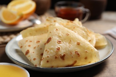 Photo of Delicious crepes and honey on wooden table, closeup