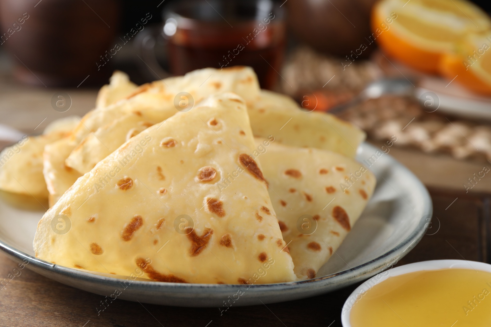 Photo of Delicious crepes and honey on wooden table, closeup