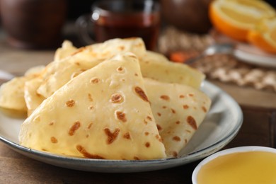 Photo of Delicious crepes and honey on wooden table, closeup