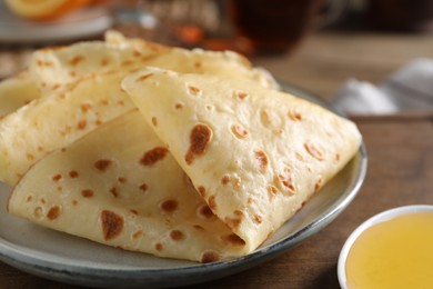 Photo of Delicious crepes and honey on wooden table, closeup