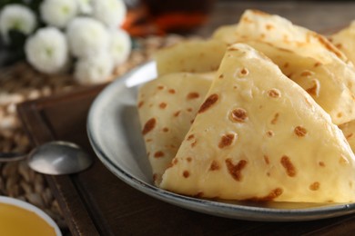 Photo of Plate with delicious folded crepes on table, closeup