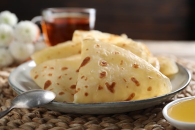 Photo of Delicious crepes, honey and spoon on table, closeup