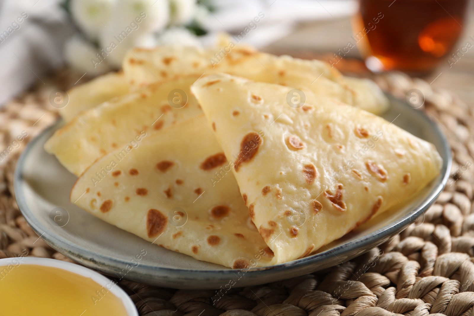 Photo of Delicious crepes and honey on table, closeup