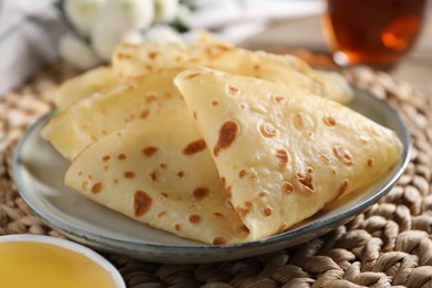 Photo of Delicious crepes and honey on table, closeup