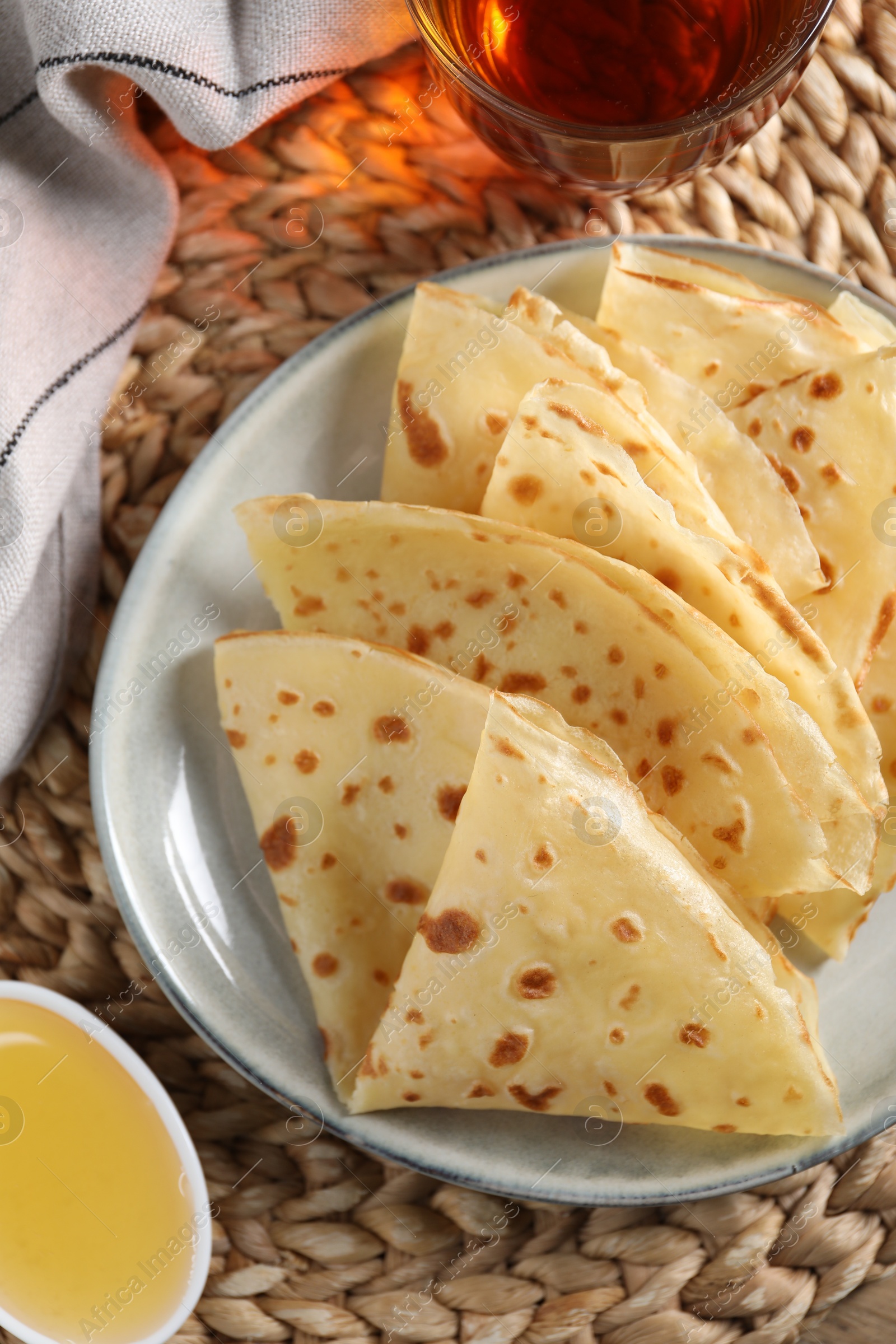 Photo of Delicious crepes, honey and tea on table, flat lay