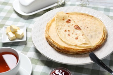 Photo of Delicious crepes, tea and butter on table, closeup view