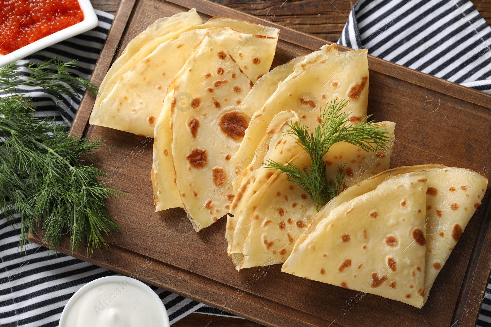 Photo of Delicious crepes, dill, red caviar and sour cream on table, flat lay