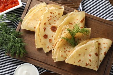 Photo of Delicious crepes, dill, red caviar and sour cream on table, flat lay