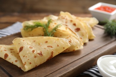 Photo of Delicious crepes, dill and sour cream on table, closeup