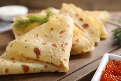 Photo of Delicious crepes and red caviar on table, closeup