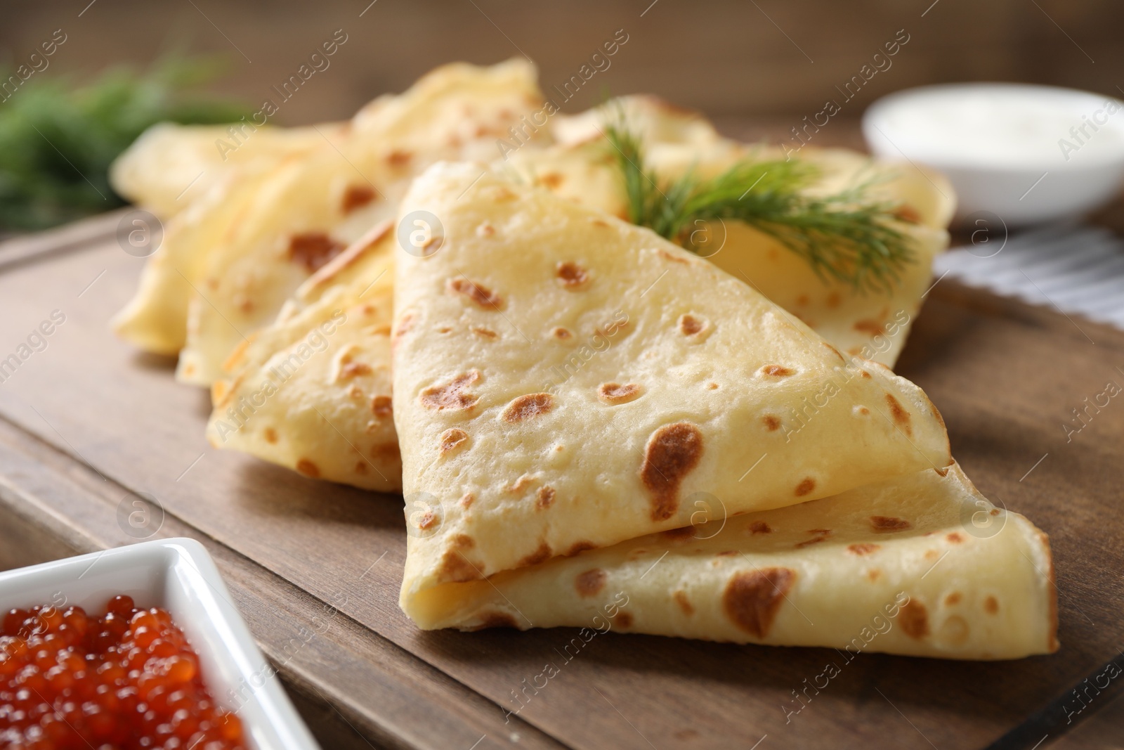 Photo of Delicious crepes and red caviar on table, closeup