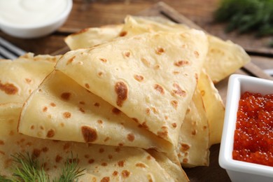 Photo of Delicious crepes and red caviar on table, closeup