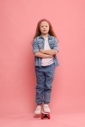 Photo of Little girl with penny board on pink background