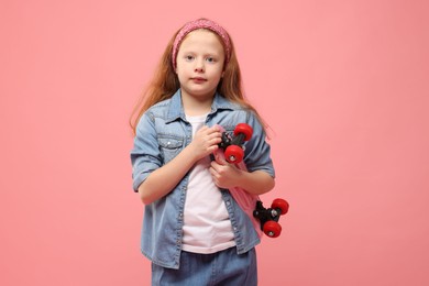 Photo of Little girl with penny board on pink background