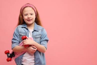 Photo of Little girl with penny board on pink background, space for text