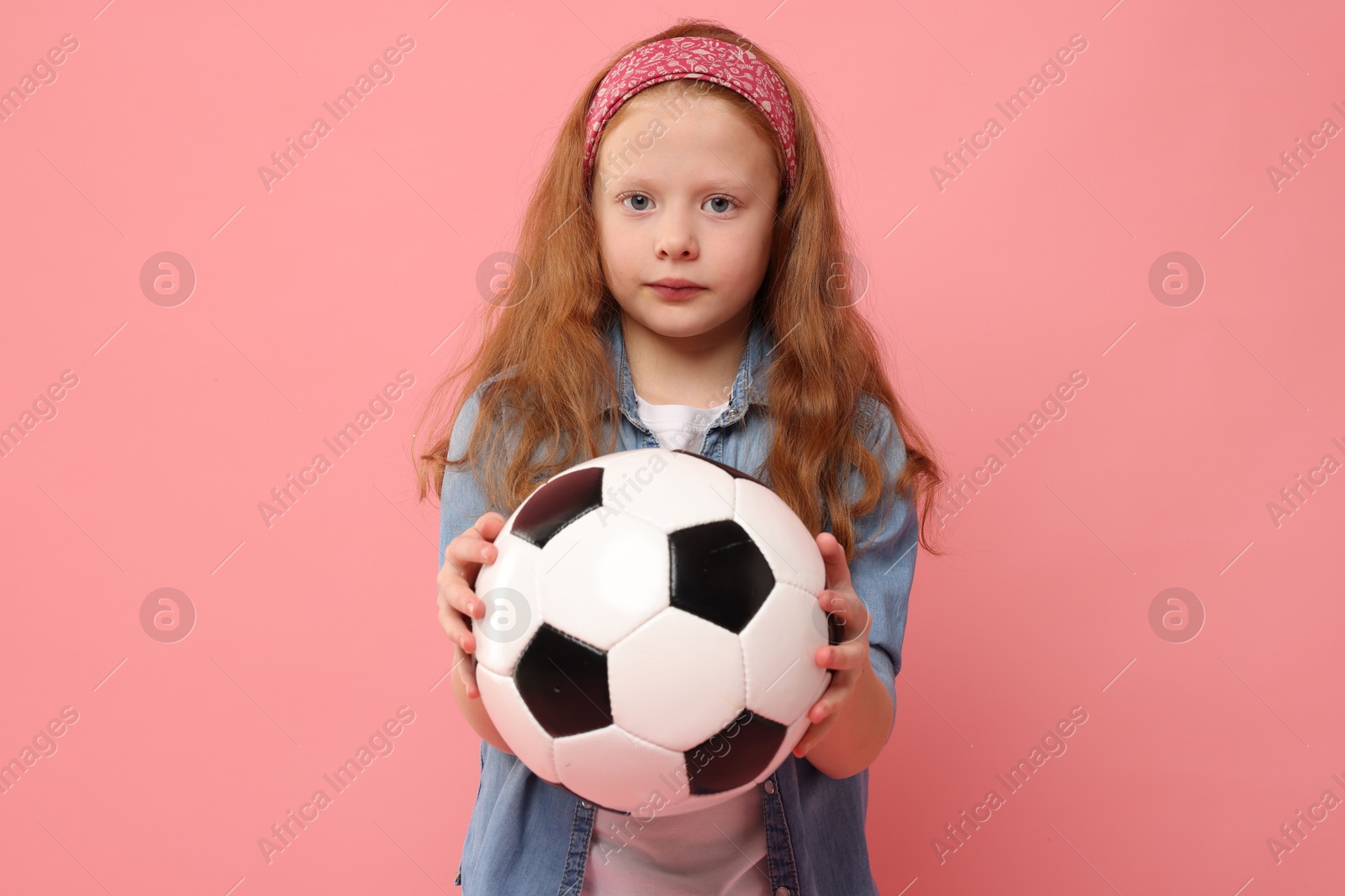 Photo of Little girl with soccer ball on pink background