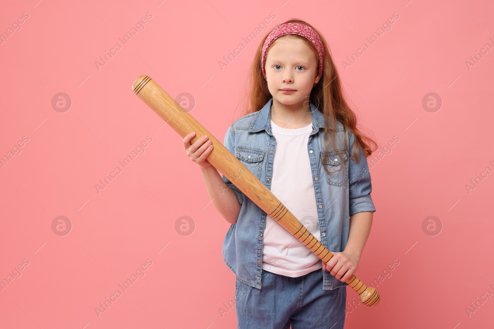 Photo of Little girl with baseball bat on pink background