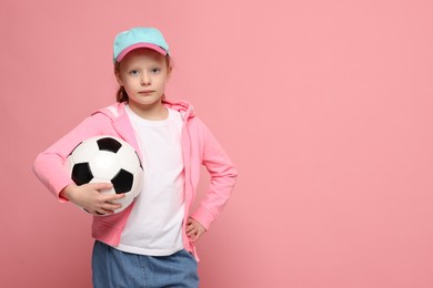 Photo of Little girl with soccer ball on pink background, space for text