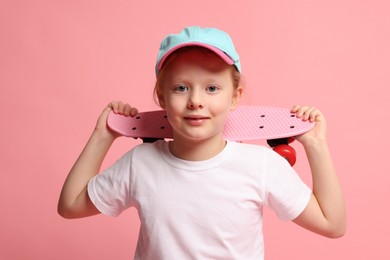 Photo of Little girl with penny board on pink background